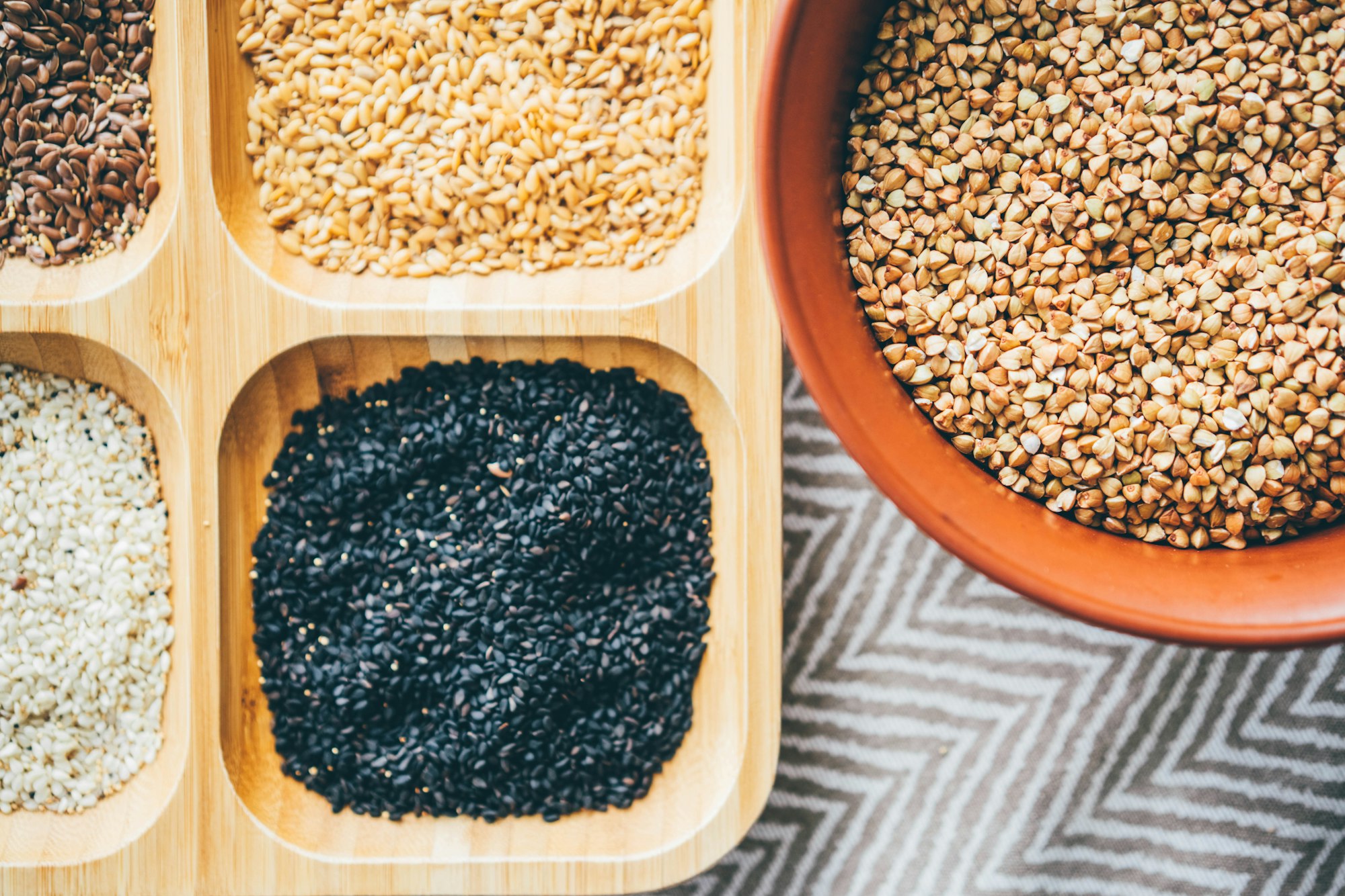 wooden dish with set of different raw seeds of hemp and linseed in special sections